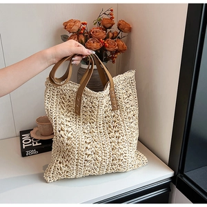 Close-up of woven straw tote bag with reinforced brown leather handles in a cozy setting
