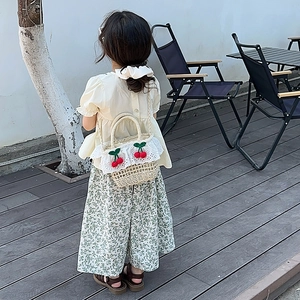 Straw woven crossbody bag for kids featuring delicate lace trim and red cherry accents