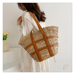 Detail of hand-woven straw tote bag with brown leather straps and drawstring inner