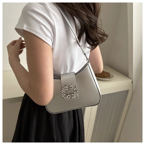Detail of silver metallic underarm bag with a large sparkling rhinestone buckle