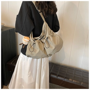 Detail of khaki nylon crossbody bag with dual drawstring pockets and plush charm