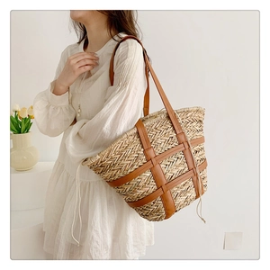 Detail of woven straw tote bag with brown leather cross-frame and cream drawstring closure