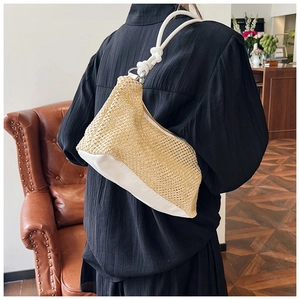 Detail view of woven straw shoulder bag with white PU base and thick rope handle straps