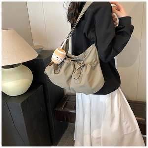 Detailed side view of khaki canvas crossbody bag with cute coffee cup plush charm