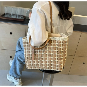 Détail du sac cabas en paille avec anses en cuir marron et motif de maille géométrique