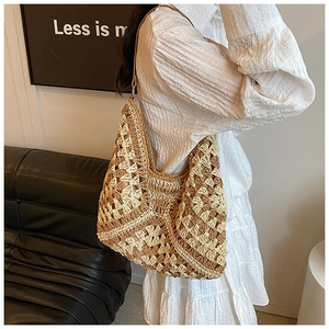 Detail of hollow woven straw tote bag in beige with slim brown shoulder straps