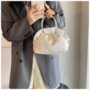 Detail of minimalist beige PU crossbody bag with Chinese embroidery and silver handle