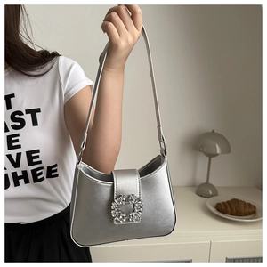 Macro shot of metallic silver faux leather baguette bag with sparkling crystal buckle