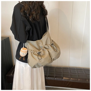 Detail of khaki nylon crossbody bag with drawstring pockets and plush coffee cup charm