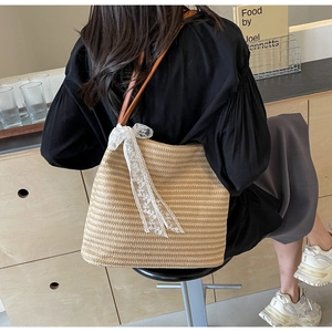 Gros plan du sac cabas beige tressé avec nœud en dentelle et bandoulière en cuir