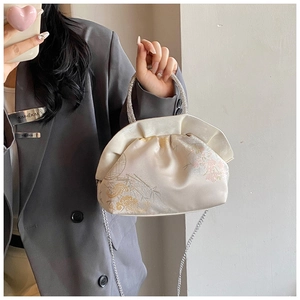 Detailed view of cream satin handbag featuring intricate floral embroidery and rhinestone handle