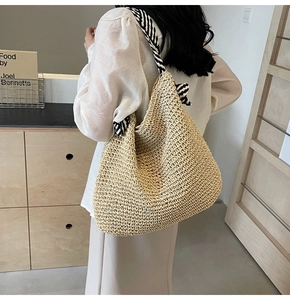 Détail d'un sac à bandoulière en paille avec sangle rayée noire et blanche sur mannequin