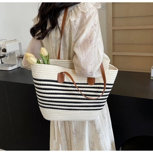 Detail of woven white cotton rope tote bag with black stripes and brown leather handles