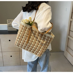 Détail du grand sac cabas en paille présentant une texture tissée et des anses en cuir brun