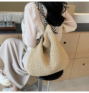 Détail d'un sac cabas en paille tissée avec des bandoulières nouées à rayures bicolores