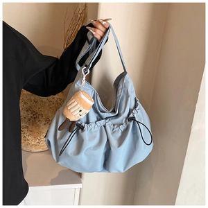 Detail of light blue cloud pleated crossbody bag with a cute plush charm and drawstring