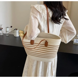 Detail of hand-woven tote bag with beige stripes and leather strap in a lifestyle setting