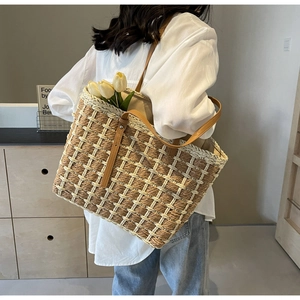 Détail du sac cabas en paille tressée avec lanières en cuir marron et texture à carreaux