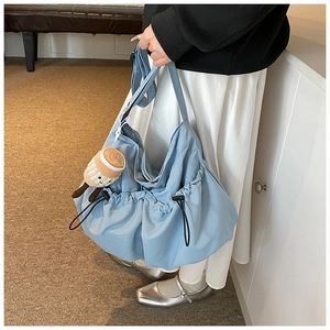 Light blue nylon crossbody bag featuring a slouchy design and a plush coffee cup charm