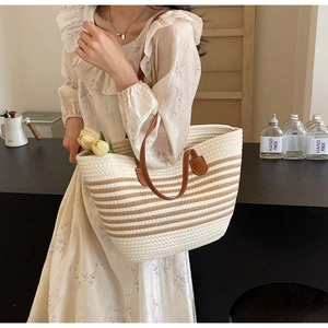 Detail of the woven tote bag showing neutral stripe pattern and premium leather handles