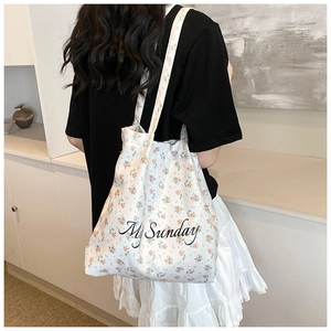 Detail of white floral canvas tote bag with My Sunday text print on a female model