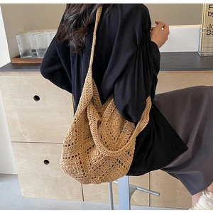 Détail du sac à main en paille tressée avec motifs évidés et longue bandoulière réglable
