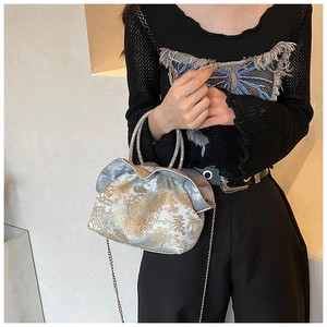 Detail of silver gray brocade evening bag with golden embroidery and rhinestone handles