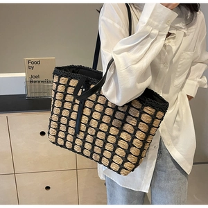 Détail d'un grand sac cabas en paille tressée avec motif quadrillé noir sur un mannequin
