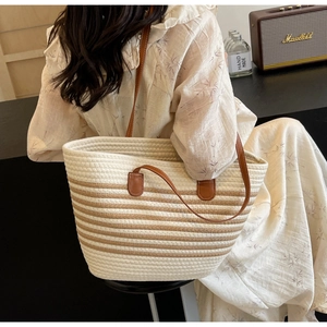 Detail of hand-woven off-white tote bag with brown stripes and leather handles in cafe