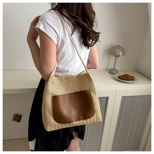 Détail du sac à bandoulière en paille tissée avec poche en cuir brun et anses en coton blanc