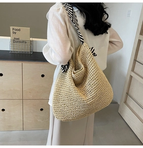 Détail d'un sac cabas en paille beige avec bandoulière tissée à rayures noires et blanches
