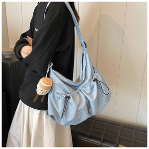 Detail of light blue nylon crossbody bag with drawstring pleats and plush charm on strap