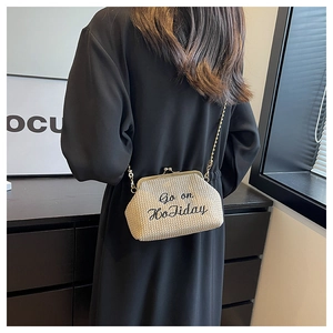 Détail du sac à main beige en paille tressée avec broderie et bandoulière chaîne dorée