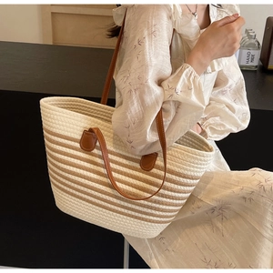 Detailed texture of handwoven tote bag featuring cream cord and brown leather straps