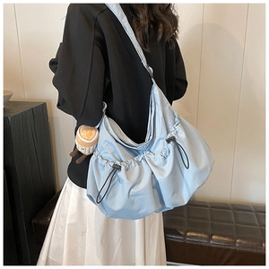 Detail of light blue slouchy nylon crossbody bag featuring drawstring pleated design