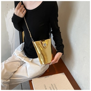 Dettaglio di una borsa a tracolla in pelle PU dorata con finitura metallica e catena