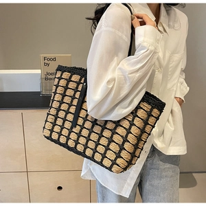 Sac fourre-tout en paille avec bordure noire et lanières dans un décor minimaliste