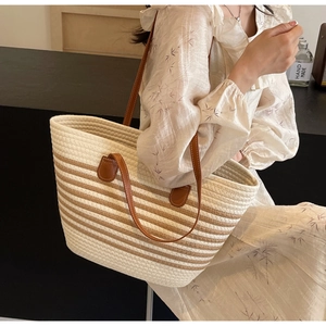 Detail of woven rope tote bag with brown leather straps and striped texture