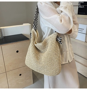 Détail d'un sac hobo en paille tressé avec bandoulière à motifs noirs et blancs
