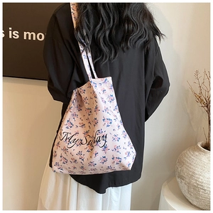 Close-up of pink floral canvas tote bag featuring My Sunday text worn by a model