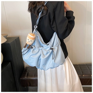 Detail of light blue fabric tote bag with brown drawstring and coffee cup plush charm
