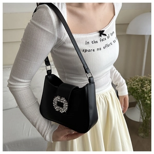 Detail of classic black baguette bag with rhinestone buckle on model in home setting