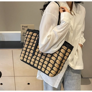 Détail d'un sac cabas en paille tressé avec motif quadrillé noir et anse en cuir