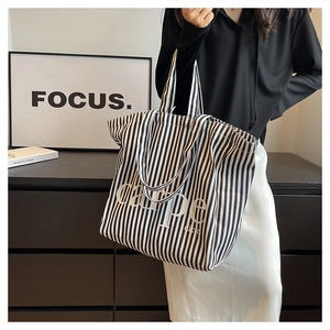 Black and white striped canvas tote bag with Carpe Diem print held by a model