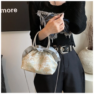 Detail of golden jacquard cloud bag with silver ruffled edge and crystal ring handle