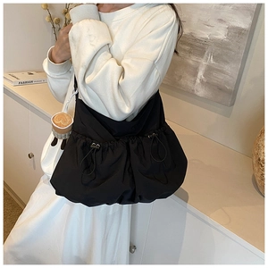 Close-up of black nylon tote bag with drawstring pockets on a model in a modern room