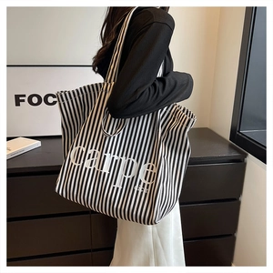 Detailed view of striped canvas tote bag with Carpe Diem print in minimalist setting