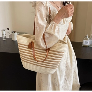 Detailed macro view of woven tote bag texture with brown leather straps and striped pattern