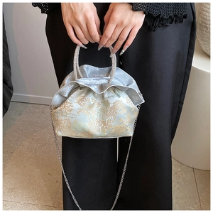 Detail of light blue satin crossbody bag with golden embroidery and diamond-set handle