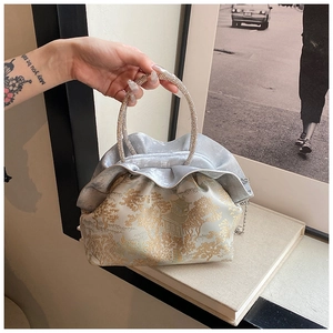 Detail of vintage style crossbody bag with silk pleats and golden jacquard patterns